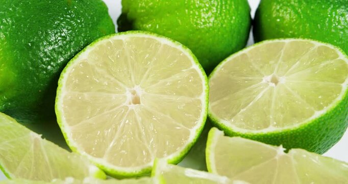 Ripe Lime Fruits with Slices and Lime Halves Slowly Rotating on a White Background. Macro Video Shooting