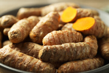 Tumeric rhizomes in bowl on table, closeup