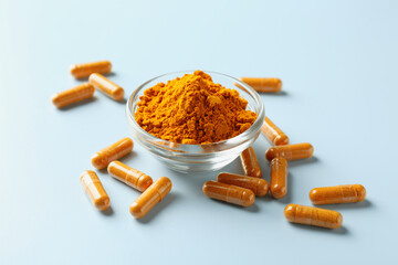 Turmeric capsules and powder on light blue background, closeup