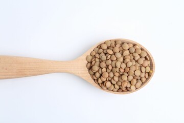 Raw lentils in wooden spoon isolated on white, top view