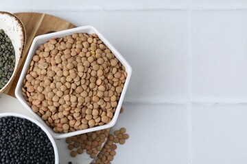 Different types of lentils on white tiled table, top view. Space for text