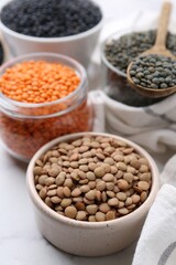 Different types of lentils on white table, closeup
