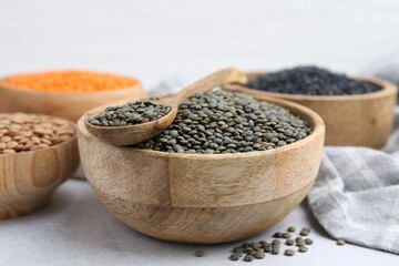 Different types of lentils on light table, closeup