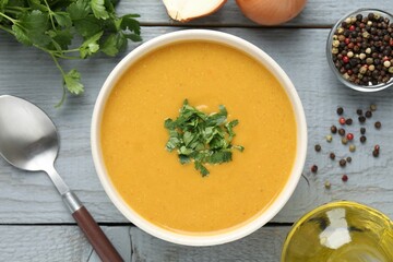 Delicious lentil cream soup with parsley served on grey wooden table, flat lay