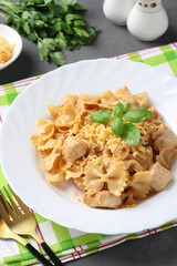Pasta farfalle with turkey in tomato-sour cream sauce, served cheese and basil on white plate