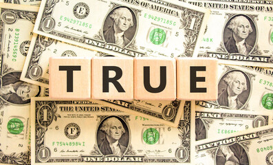 True symbol. Concept word True on beautiful wooden blocks. Dollar bills. Beautiful background from...