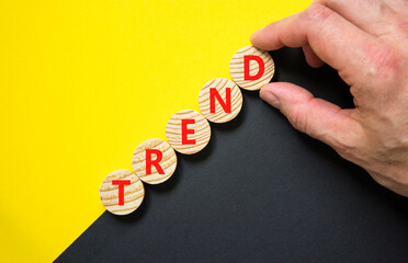 Trend and trending symbol. Concept word Trend on beautiful wooden circles. Beautiful yellow and black background. Businessman hand. Business lifestyle trend and trending concept. Copy space.