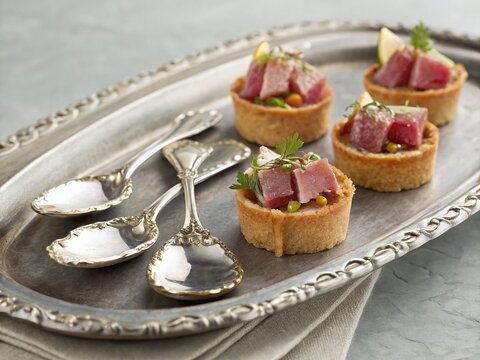Cold tuna appetizer with fancy serving spoons on an elegant silver tray