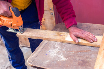 close up of carpenter that work on woodworking using electric jigsaw for wood.