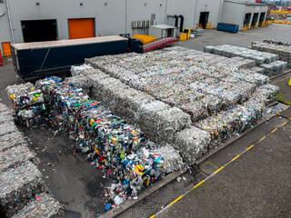 Bales of plastic waste including food packaging and milk cartons at a recycling plant