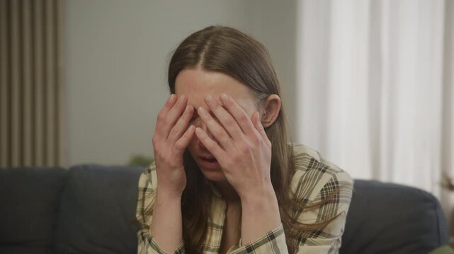 Shocked Woman Holding Head In Hands After Receiving Devastating News Indoors