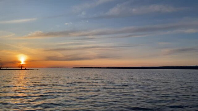 Sunset Over Lake with Silhouetted Trees and Reflected Sky, The sky reflects in the water while soft clouds