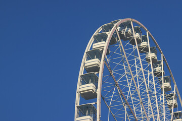 Ferris wheel against blue sky. Amusement park. Close-up of Ferris wheel cabins
