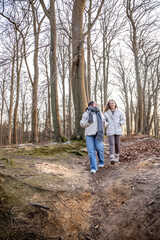 Fototapeta premium Two female friends on a walk in the forest. Friends walking through the forest. People in nature.