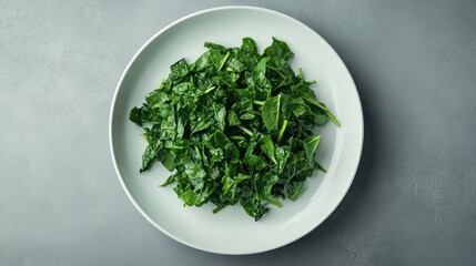 Green leafy vegetables chopped on a white plate against a gray background.