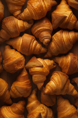 Naklejka premium A background of golden brown croissants showing flaky texture and rich layers. Perfect for bakery promotions and culinary visuals.