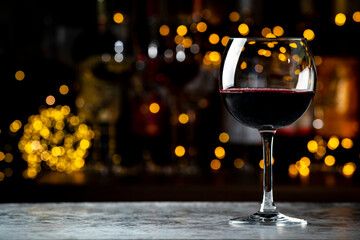 Italian dry red wine chianti glass and wine bottles on dark bar background with lights