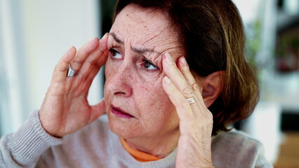Mature woman enduring intense headache, eyes closed, hands on temples. Expression and facial lines...