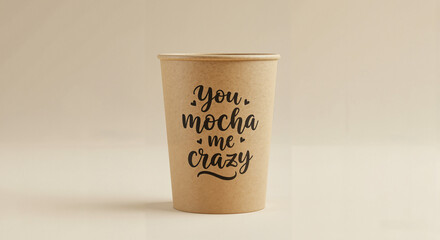 Kraft cup with playful hand lettering You mocha me crazy against clean beige background, straight-on view with soft light, cheerful and flirty message