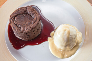 Chocolate fondant with strawberry sauce and a scoop of ice cream on a wooden table, desserts