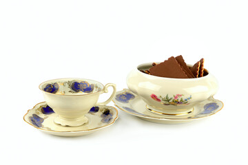 Vintage porcelain candy bowl ,chocolate chip cookies, cup and saucer isolated on white.