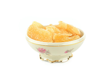 Candied ginger in a porcelain bowl isolated on white.