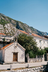 Fototapeta premium Small stone church of St. Michael near an old house with a red roof. Dobrota, Montenegro