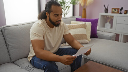 Man reading letter on sofa in cozy apartment living room