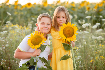 Children - a boy and a girl in a field with sunflowers in summer