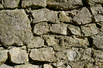Fototapeta premium Detailed close up view of a rough irregular stone wall texture. Natural pattern of rocks and mortar ideal for background or surface concepts showing strength and rustic style