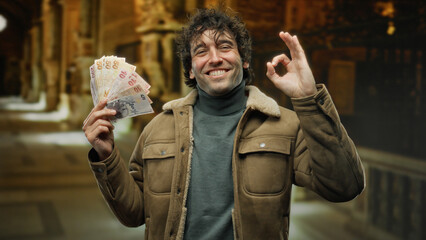 Man with turkish lira smiling indoors at museum holding banknotes confidently showing gesture...