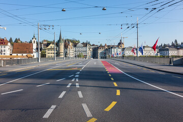 Lucerne, Switzerland: Deserted street and pedestrian walkway, under a clear blue sky. The street is...