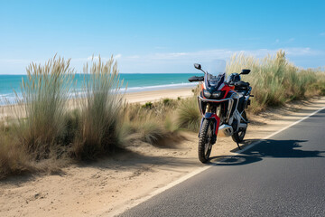Obraz premium Motorcyclist riding along coastal road with scenic beach backdrop 