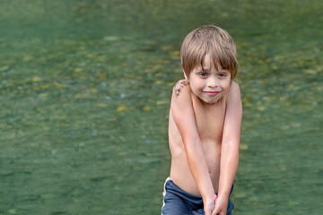 Fototapeta premium Wet boy coming out of the water. He is cold, he is frozen.