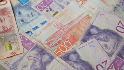 Swedish banknotes in various denominations, including 20, 50, 100, 500, and 200 kronor, spread out in a visually appealing layout.