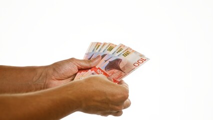 Hand holding norwegian krone banknotes over isolated white background