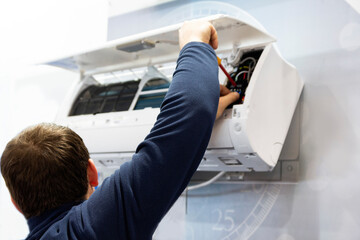 A male air conditioner technician or air conditioning installation. technician is about to repair...