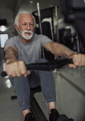 Retired sportsman working out using equipment in gym