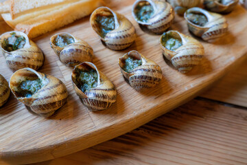 Escargot with garlic butter on wooden platter