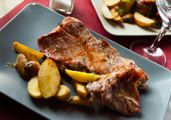 Close up of tasty cooked fried pork with fried potatoes at plate