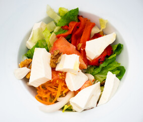Traditional spanish vegetarian salad with fresh cheese and walnut on a white ceramic plate