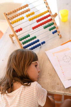 Child resting by abacus on homework table with papers