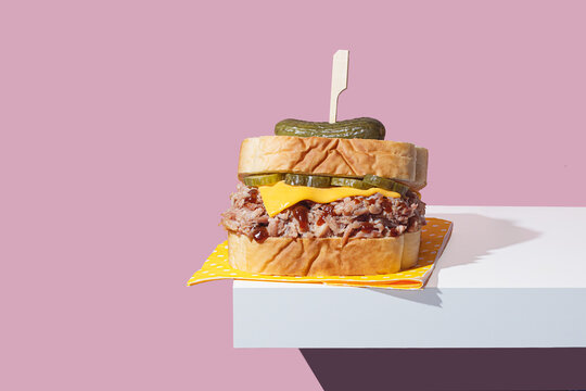 Pulled pork sandwich with cheddar and pickles on modern background