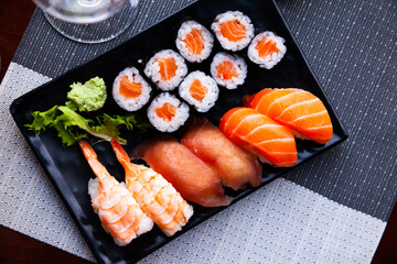 Various sushi served on black plate. Japanese food, nobody