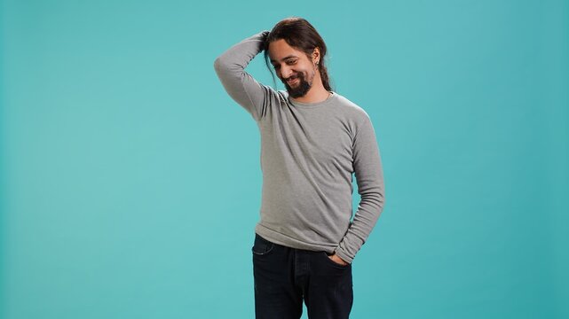 Portrait of shy man putting hand on head, feeling ashamed, isolated over studio shot. Self conscious person feeling insecure while seeing crush, feeling need to express emotions, camera A