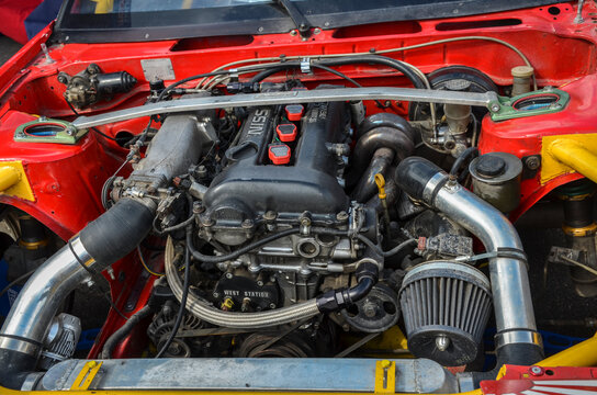 Close-up of a modified car engine bay of Nissan 200SX S13 including a turbocharger, intercooler piping, and a performance air filter