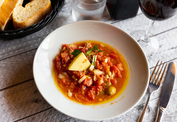 Mojete con queso, popular cold dish of spanish cuisine at Castilla La Mancha autonomous community of Spain. Chopped tomatoes, canned tuna, eggs, olives, oil and spices, served with slice of cheese