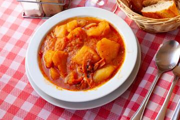 Appetizing stewed calamari with potato served in white bowl. Seafood delicacy