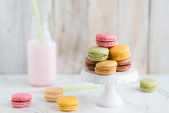Bottle of  strawberry milk with strawberry, chocolate, lemon, pistachio and coffee macarons (french macaroons) on a cakestand