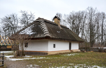 Rustic countryside house featuring a snowy setting and a traditional thatched roof, surrounded by a...